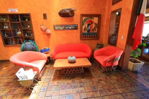 a room with two red chairs and a table at Villa Mexicana Creel Mountain Lodge in Creel