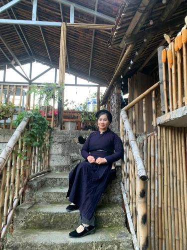 a woman sitting on the stairs of a building at Trường Giang homestay Bản Giốc in Dam Thuy