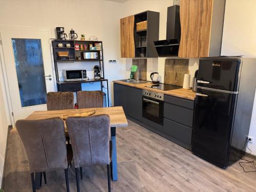 a kitchen with a wooden table and a black refrigerator at Naumburger Charme Solaris II in Naumburg