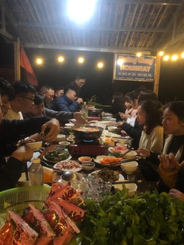 a group of people sitting at a long table with food at Trường Giang homestay Bản Giốc in Dam Thuy