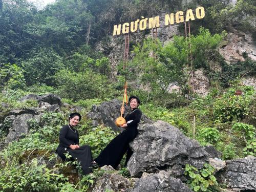 two people sitting on a rock with a guitar at Trường Giang homestay Bản Giốc in Dam Thuy