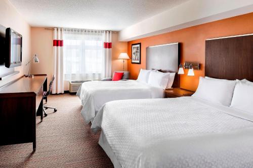 a hotel room with two beds and a desk at Four Points by Sheraton Barrie in Barrie