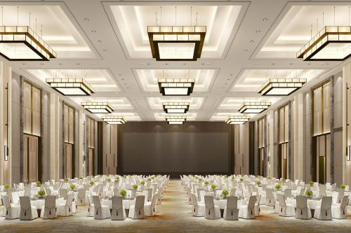 a conference room with white chairs and a projection screen at Four Points by Sheraton Jiaxing in Jiaxing