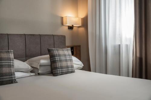 a bedroom with a bed with pillows and a window at Miramonti Park Hotel in Bormio