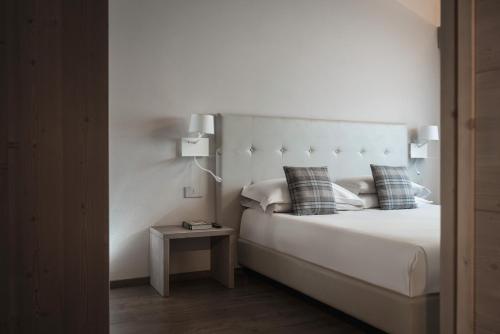 a white bed with two pillows and a side table at Miramonti Park Hotel in Bormio