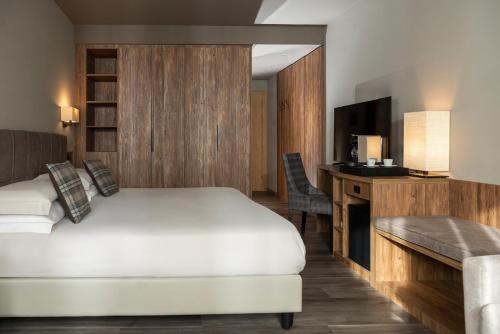 a hotel room with a bed and a desk and a television at Miramonti Park Hotel in Bormio