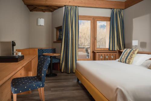 a hotel room with a bed and a desk and a window at Miramonti Park Hotel in Bormio