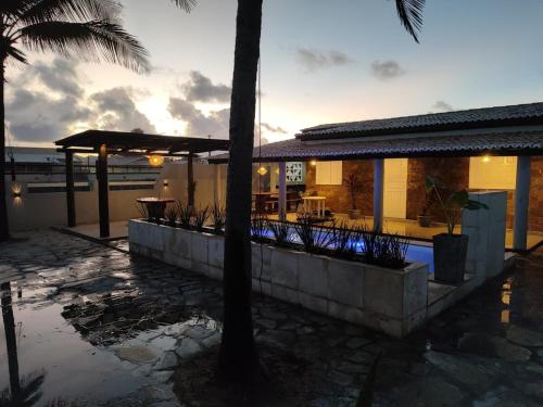 a house with a patio and a palm tree at Casa PE NA AREIA na Praia da Caueira com Piscina e SPA in Praia Da Caueira