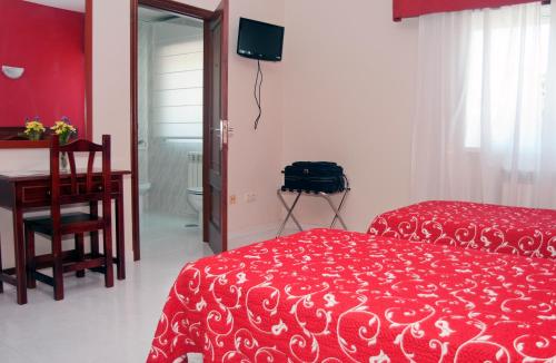 a bedroom with a red bed and a desk and a chair at Hotel Ria Toxa in Revolta