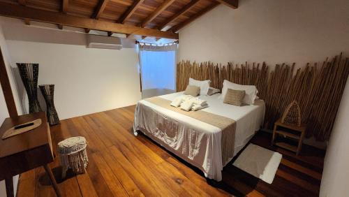 a bedroom with a bed and a wooden floor at Pousada Vila do Mar in Caraíva