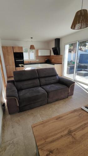 un salon avec un canapé marron et une cuisine dans l'établissement la petite villa, à Port-de-Bouc