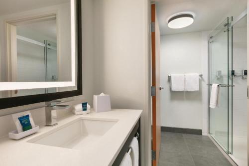 a white bathroom with a sink and a shower at Four Points by Sheraton Raleigh Arena in Raleigh