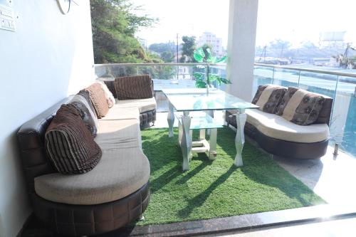 a balcony with a couch and a glass table at Dnyanprabha Executive in Tuljapur