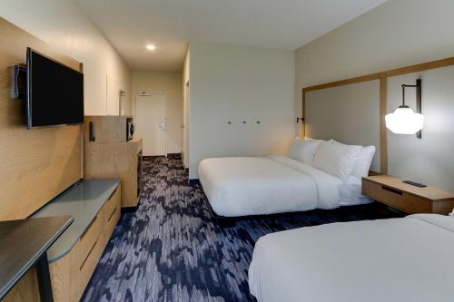 a hotel room with two beds and a flat screen tv at Fairfield Inn & Suites Southport in Southport