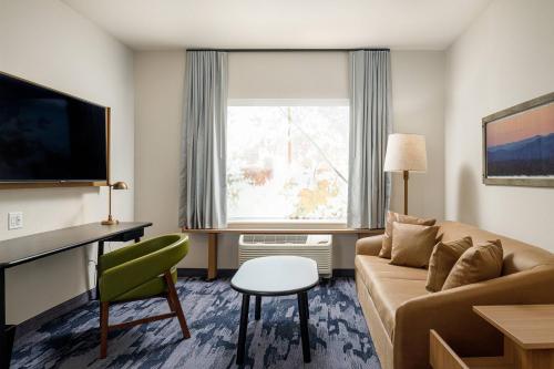 a living room with a couch and a desk and a window at Fairfield Inn & Suites by Marriott Salina in Salina