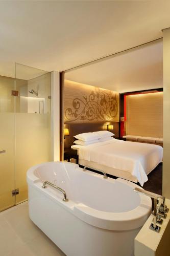 a bathroom with a bath tub and a bed at Four Points by Sheraton Bangkok, Sukhumvit 15 in Bangkok