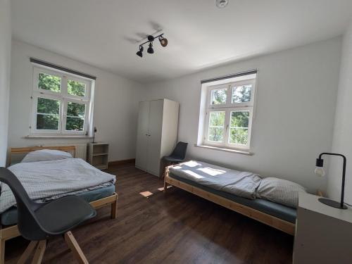 リヒテンシュタインにあるRuhige Unterkunft für 4 Personenのベッドと机と2つの窓がある寝室