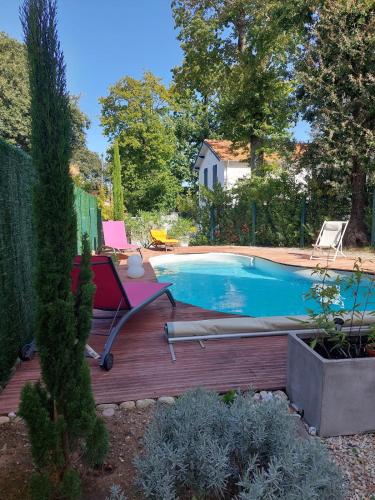 une cour arrière avec une piscine et une terrasse en bois dans l'établissement villa Parc de Royan 250 m plage, à Royan