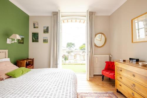 une chambre avec un lit blanc et une chaise rouge dans l'établissement villa Parc de Royan 250 m plage, à Royan