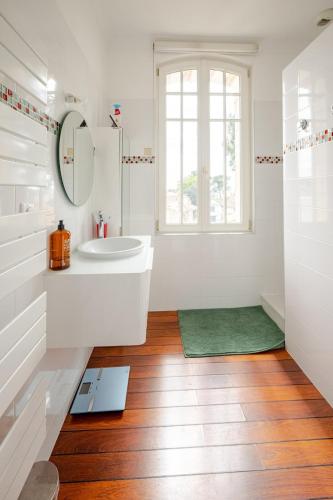 une salle de bain blanche avec un lavabo et un miroir dans l'établissement villa Parc de Royan 250 m plage, à Royan