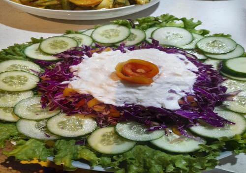 a plate of food with a salad with cucumbers and onions at Skykite Resort & Hostel Kalpitiya Sri Lanka in Kalpitiya