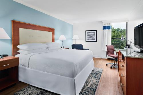 a bedroom with a large white bed and a desk at Four Points by Sheraton Richmond Airport in Sandston