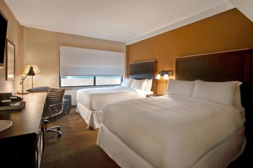 a hotel room with two beds and a desk at Four Points by Sheraton Peoria in Peoria