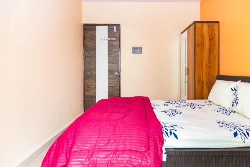 a bedroom with a bed with a red blanket at Teju's Nest in Badlapur