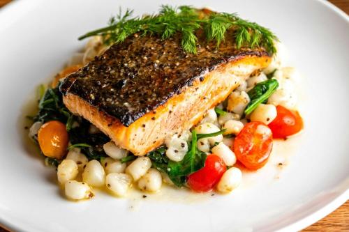 a plate of food with a piece of fish and vegetables at Four Points by Sheraton Peoria in Peoria