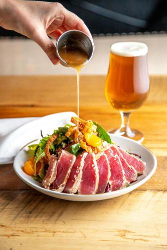 a person pouring a glass of wine over a plate of meat at Four Points by Sheraton Peoria in Peoria