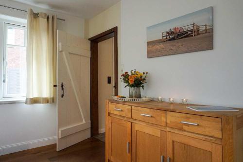 a room with a wooden cabinet with a vase of flowers on it at Ferienhaus-Min-Drom in Sankt Peter-Ording