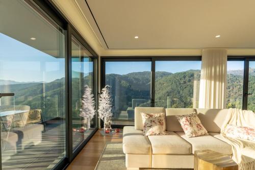 a living room with a couch and large glass windows at Waterfall View in Paradise in Louredo