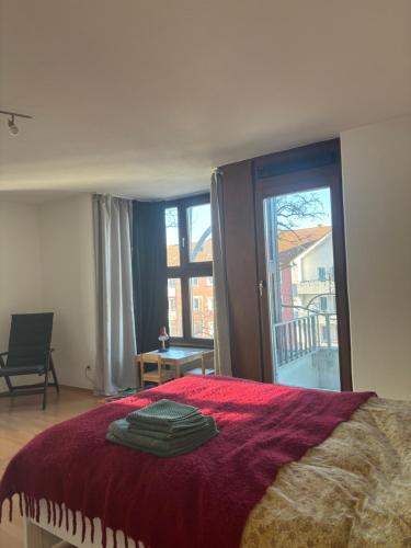 慕尼黑Studio-Apartment的一间卧室，有一张床，上面铺着红毯子，还有一扇窗户