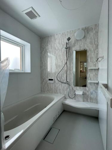 a white bathroom with a tub and a shower at Niseko Yu Villa D in Niseko