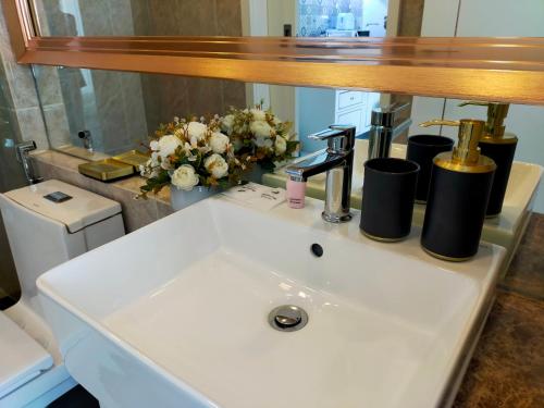 a bathroom sink with a mirror and flowers on it at The Empire Tower Jomtien KZi 2205 in Jomtien Beach