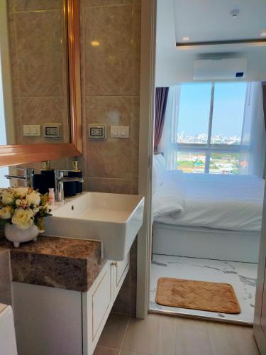 a bathroom with a sink and a bed and a window at The Empire Tower Jomtien KZi 2205 in Jomtien Beach