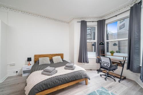 a bedroom with a large bed and a desk and window at Modern 2Bed North London Flat by D3 Short Stay, Sleeps 6, Private Yard in London