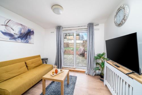 a living room with a yellow couch and a flat screen tv at Modern 2Bed North London Flat by D3 Short Stay, Sleeps 6, Private Yard in London