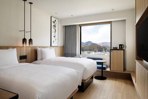 two beds in a hotel room with a window at Fairfield by Marriott Mie Okuise Odai in Odaicho