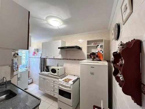a small kitchen with a refrigerator and a microwave at Ape 2 Qts - Campos do Jordão - Condomínio Alto da Boa Vista - Varanda com Vista Panorâmica - Apartamento Inteiro in Campos do Jordão