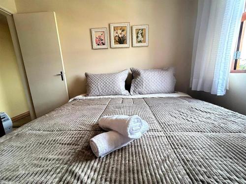 a bedroom with a large bed with a pillow on it at Ape 2 Qts - Campos do Jordão - Condomínio Alto da Boa Vista - Varanda com Vista Panorâmica - Apartamento Inteiro in Campos do Jordão