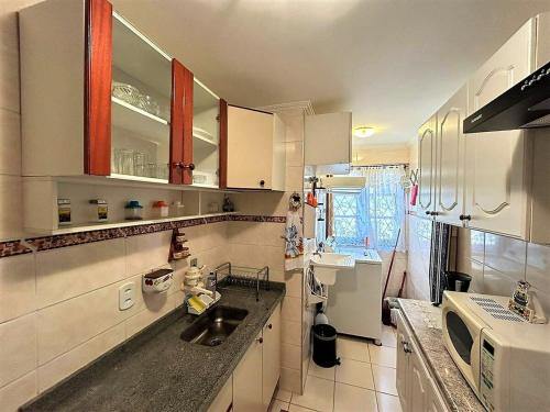 a kitchen with a sink and a microwave at Ape 2 Qts - Campos do Jordão - Condomínio Alto da Boa Vista - Varanda com Vista Panorâmica - Apartamento Inteiro in Campos do Jordão