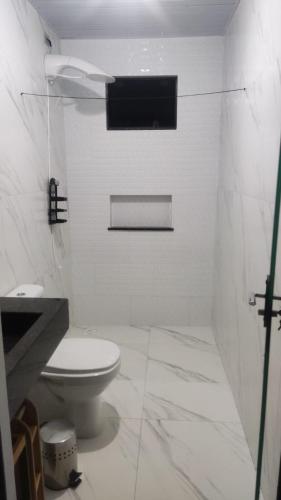 a white bathroom with a toilet and a sink at House beach da Nay in Pontal do Paraná