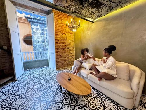 two people sitting on a couch in a living room at Hotel Villa Alta Guest House in Cartagena de Indias