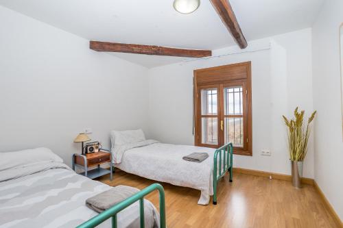 Un dormitorio con dos camas y una mesa y una ventana. en BaruHaus VillaHermosa, en Villamañán