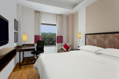 a hotel room with a bed and a desk and a window at Four Points by Sheraton Vadodara in Vadodara