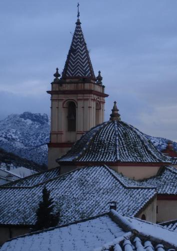 a building with a clock tower with snow covered roofs at Casa El Villa in Zahara de la Sierra