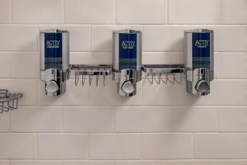 a bathroom with three soap dispensers on a wall at Four Points Philadelphia City Center in Philadelphia