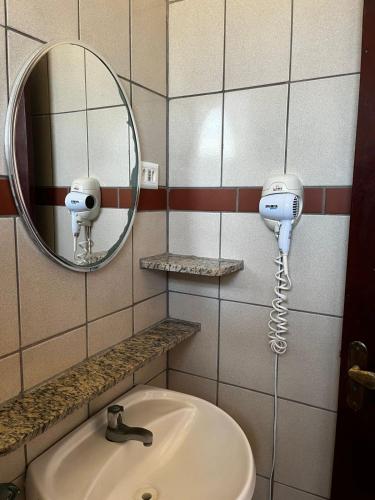 a bathroom with a sink and a mirror and a hair dryer at Pousada Weiss Blau in Ilha Comprida