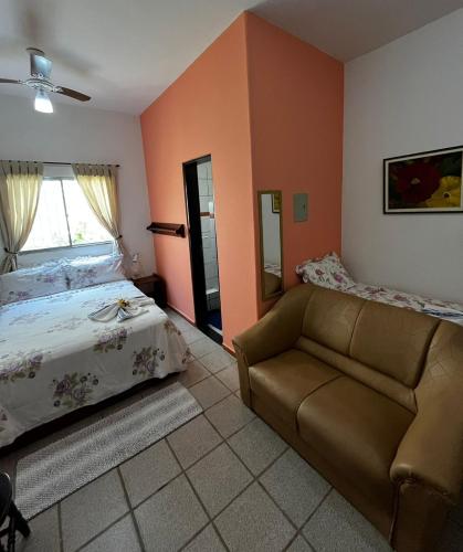 a bedroom with a couch and a bed and a window at Pousada Weiss Blau in Ilha Comprida